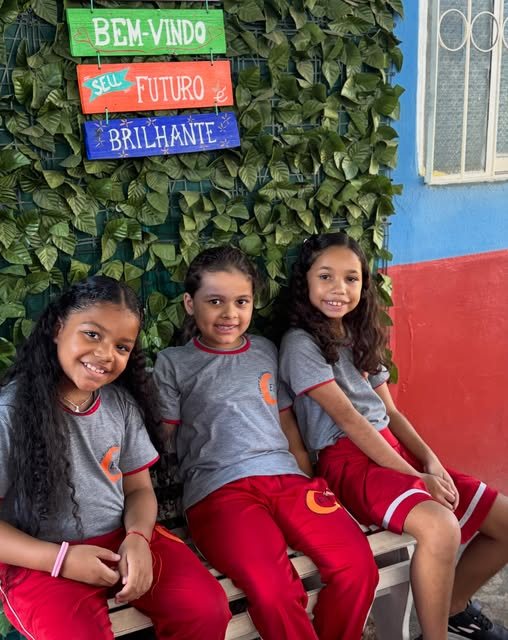 Alunas na plaquinha de boas-vindas da escola